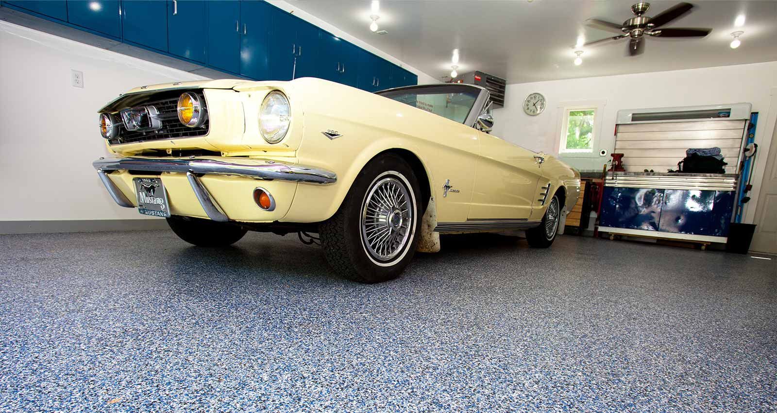 A yellow mustang convertible is parked in a garage.