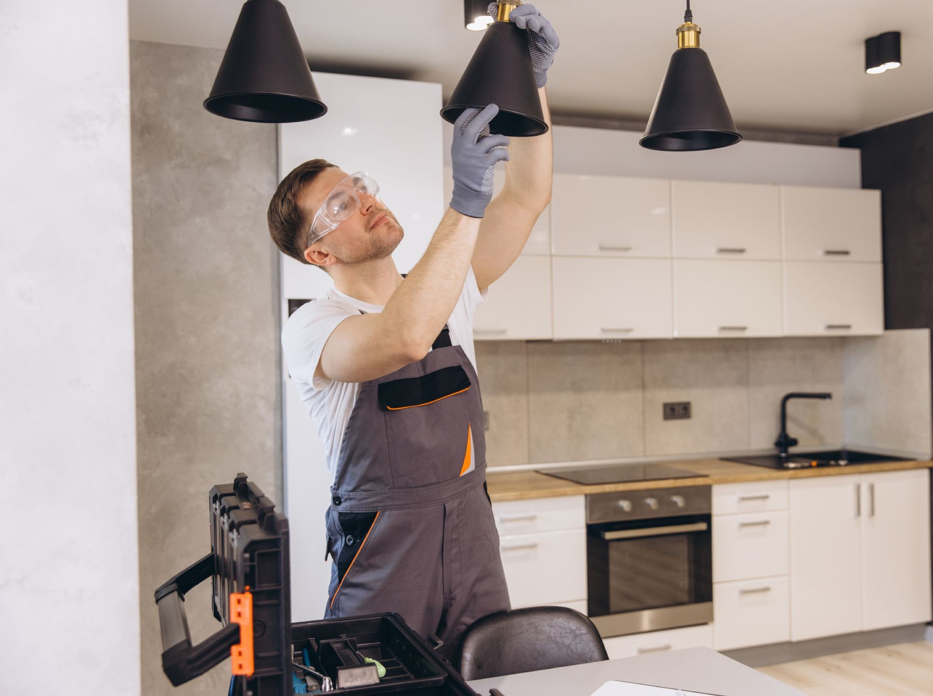 Electrician tightening a ceiling light fixture in a modern kitchen