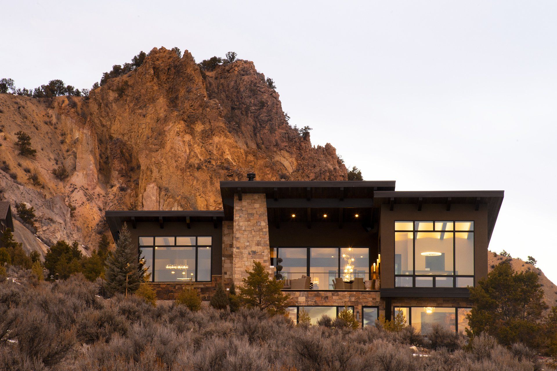 A large house sits on top of a hill with a mountain in the background