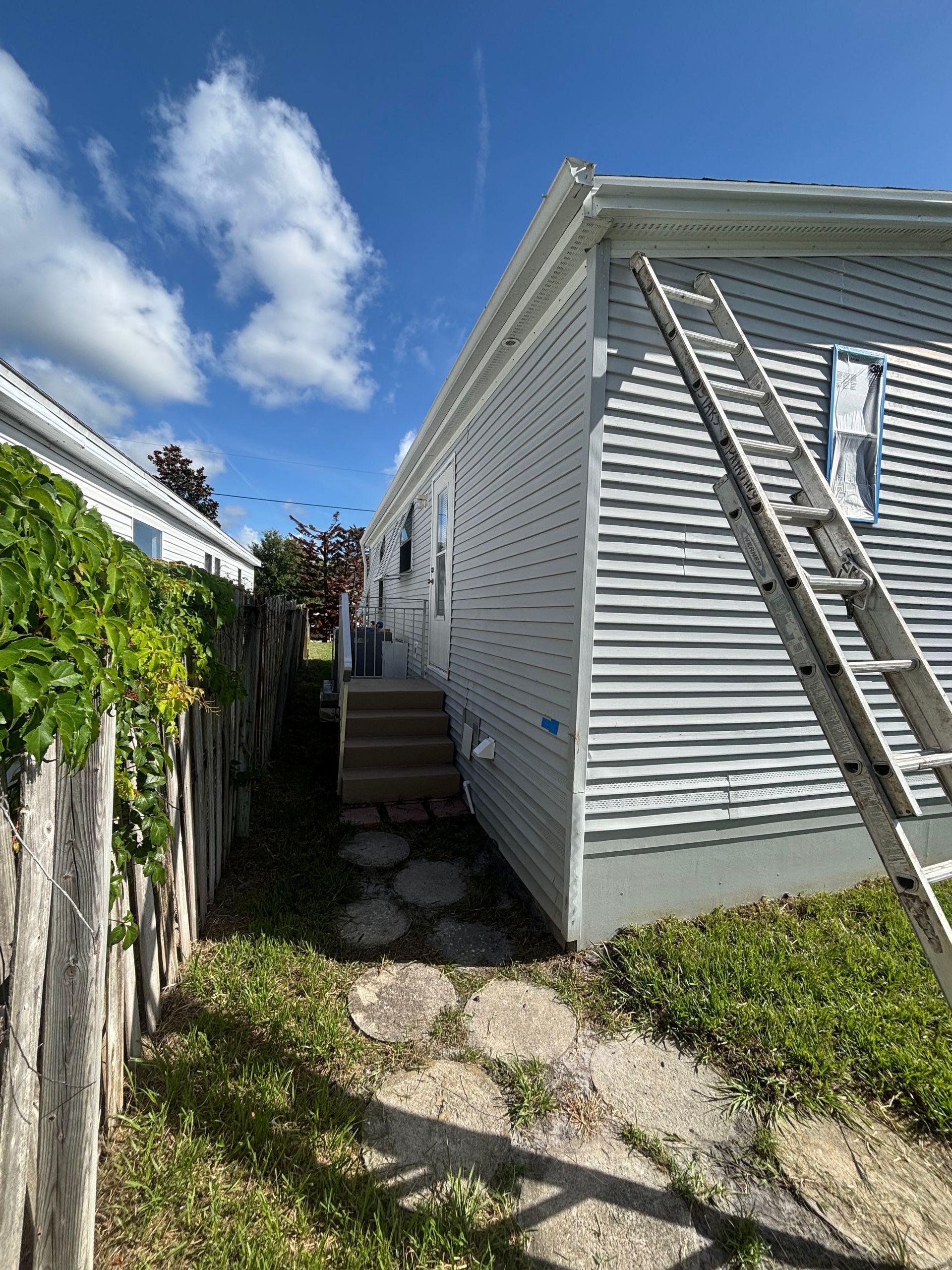Professional masking and preparation before painting a vinyl siding home in Edgewater, FL