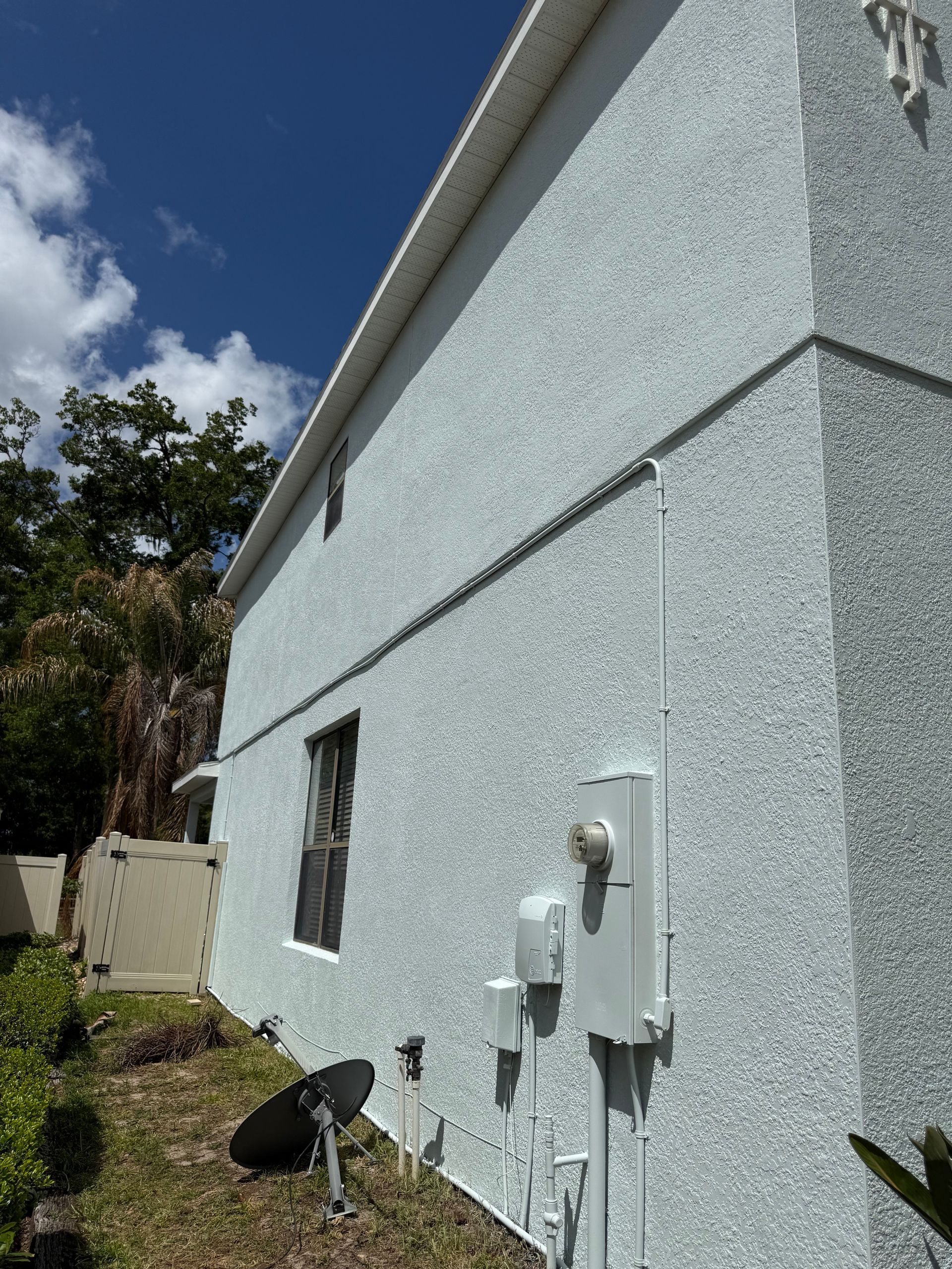 Side view of professionally painted two-story stucco house in DeLand, Florida