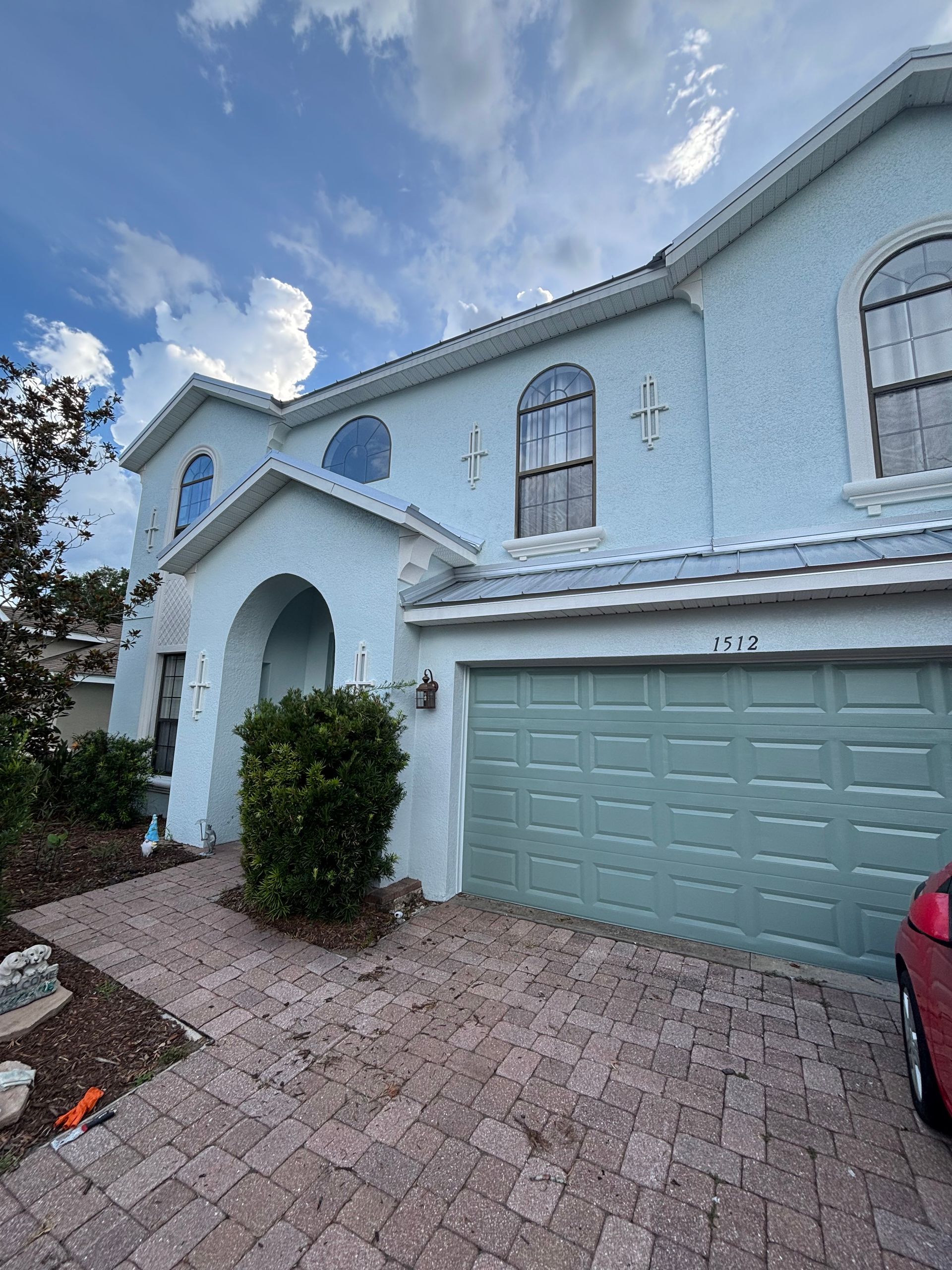 Premium exterior repaint of a stucco home with repaired cracks and refinished front door in DeLand