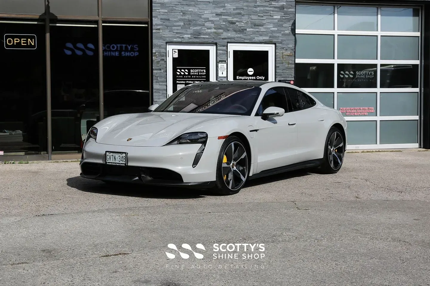Silver sports car parked outside a building with garage doors and stone facade.
