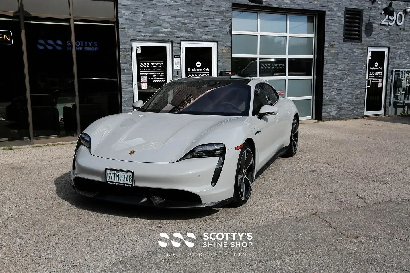 White sports car parked outside a dealership building with dark windows and a concrete lot.