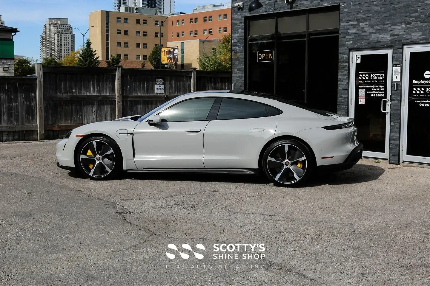 Silver sports coupe parked outside a building on a gravel lot.