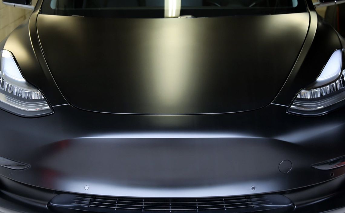 Front view of a black sports car with sleek headlights and a reflective hood