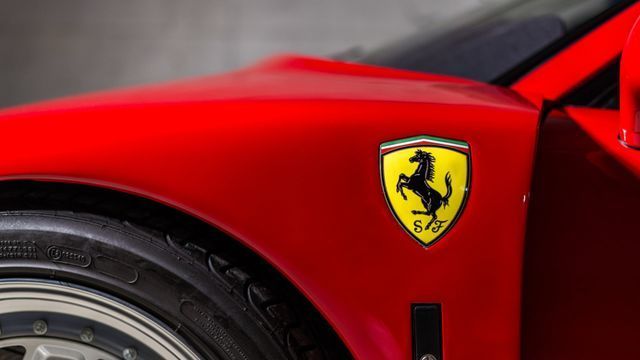 Red Ferrari car body with yellow prancing horse emblem and front wheel visible