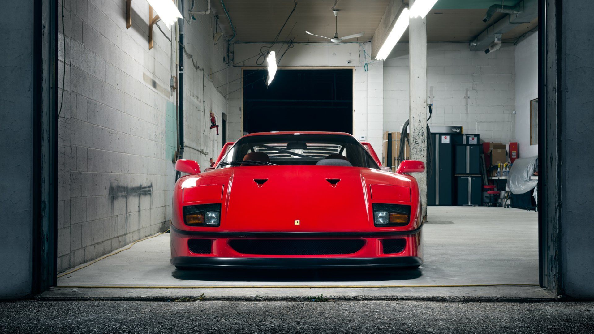 Red sports car parked in a dim garage, viewed from the front.