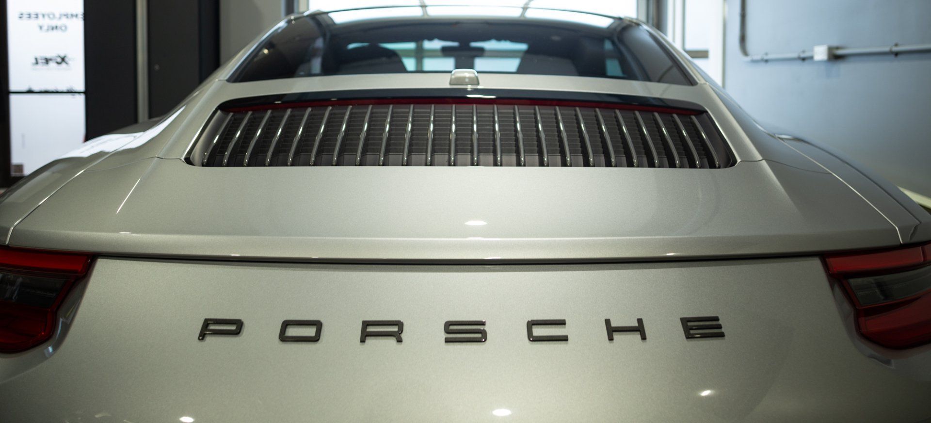 Rear view of a white Porsche sports car in a garage, with the Porsche logo on the back