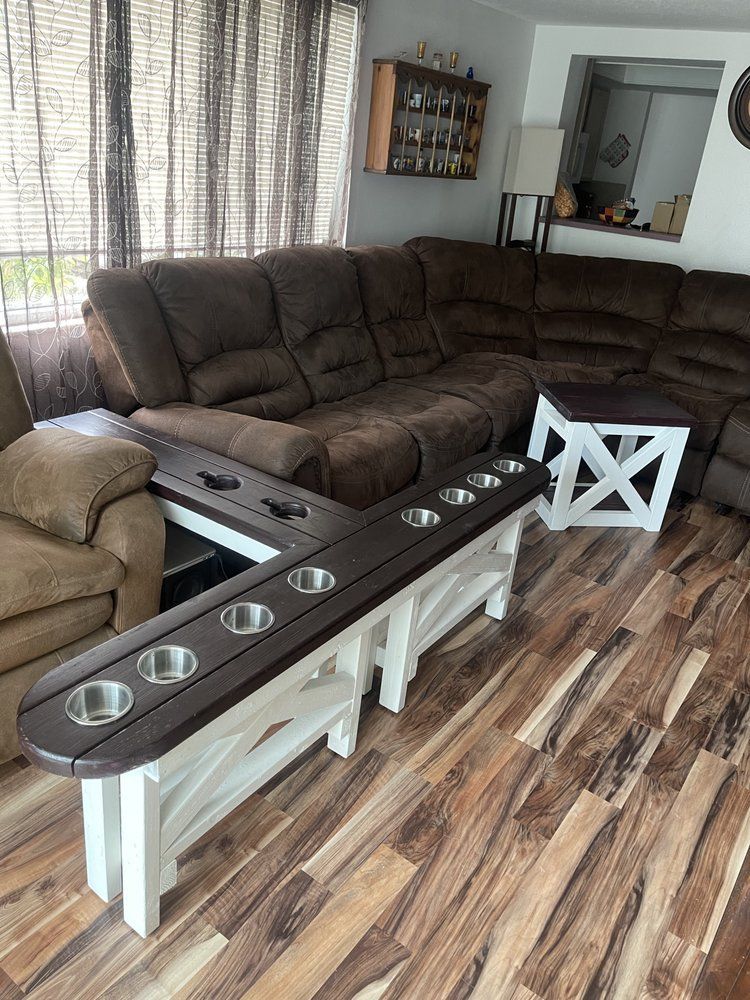 Living room with brown sectional sofa, wood-look floor, and a bar-height table with cup holders