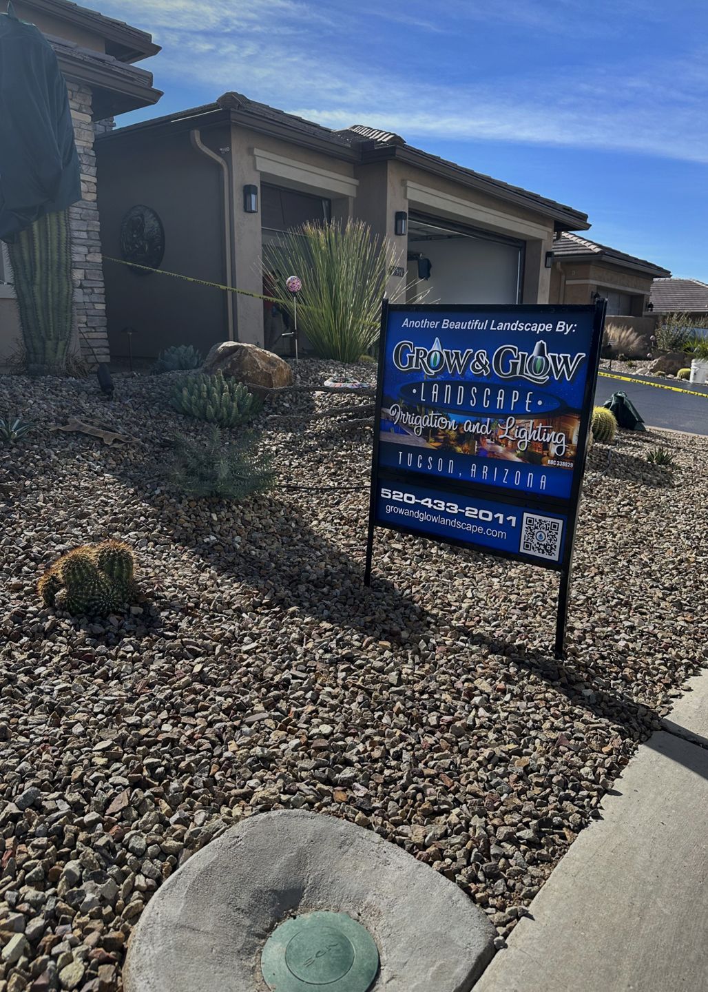 Real estate sign in front of a house. Dry landscape with rocks and a blue sky.
