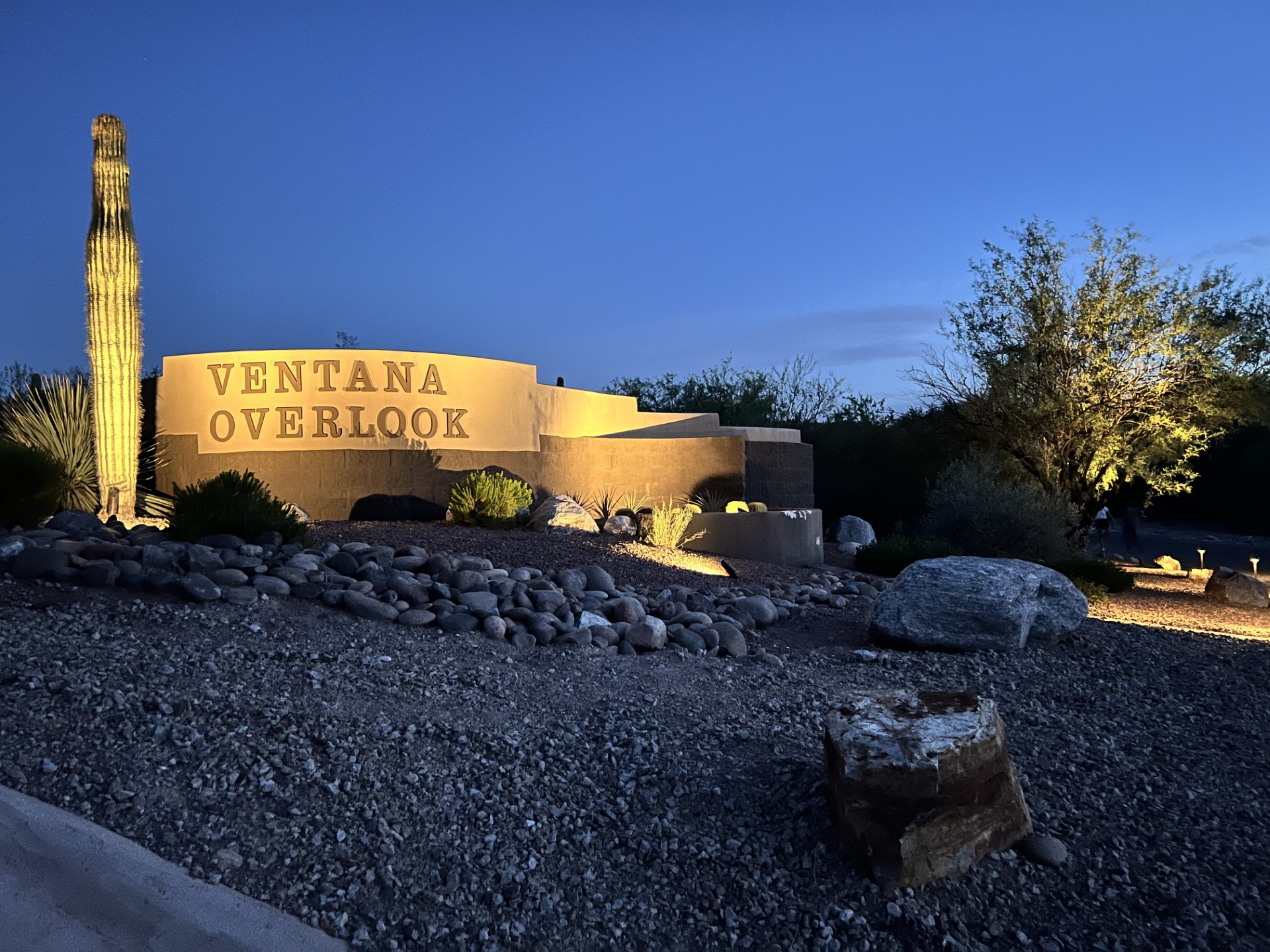 Ventana Overlook neighborhood entrance sign illuminated at dusk with desert landscaping.