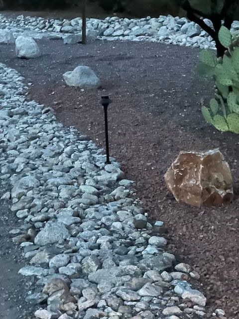 Landscape bed with a gravel border, large rocks, and a solar-powered path light.