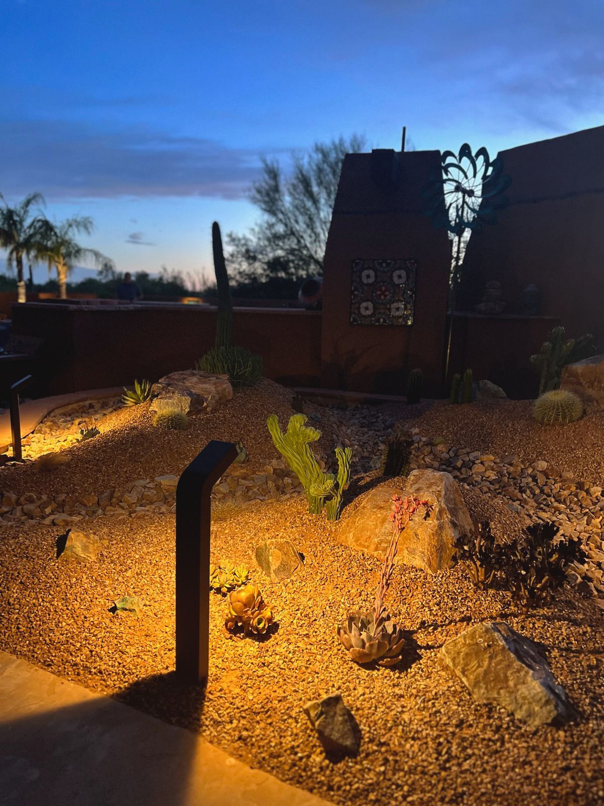 Desert landscape illuminated by path lighting at dusk.
