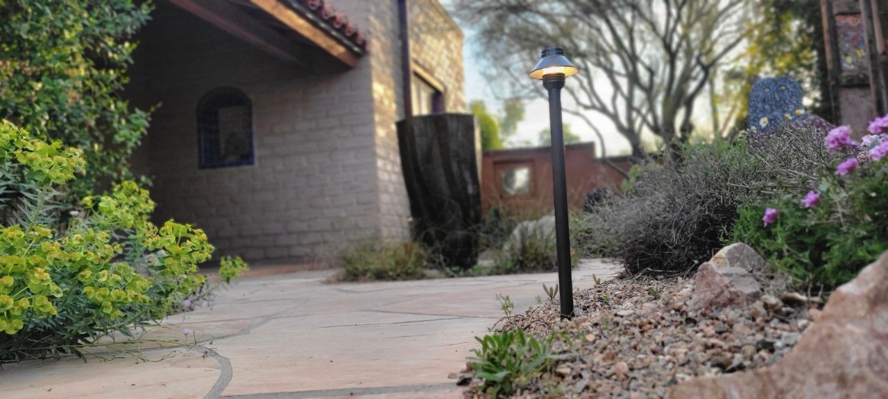 Exterior view of a stone building with a pathway and landscaping. A lamppost stands in the middle.