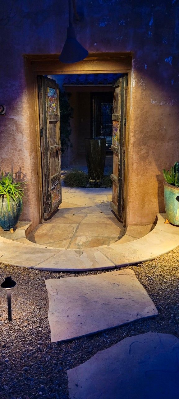 Open doorway with old wooden doors, stone walkway, and a dark blue sky.