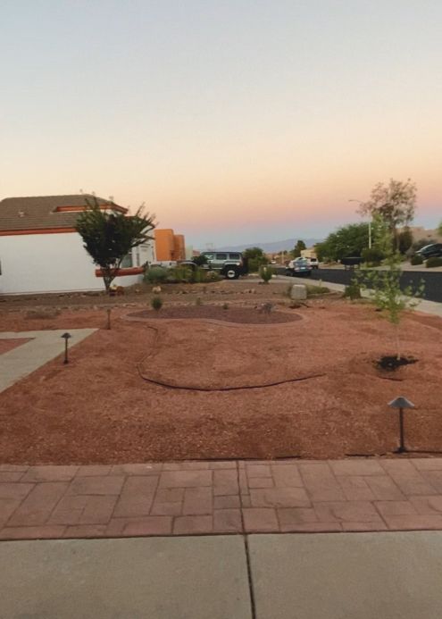 Front yard with red gravel landscaping, a winding path, and a sunset sky.