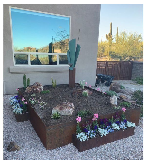 Desert landscape with metal planter boxes, a large window, and saguaro cacti.