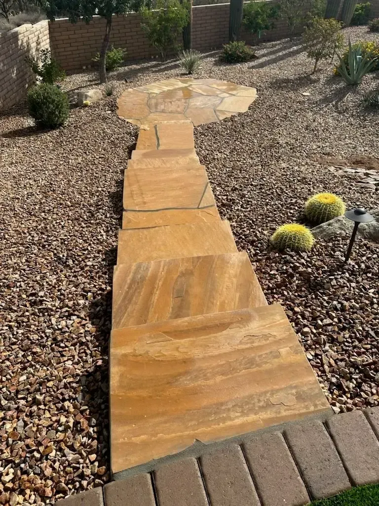 Stone pathway with steps, surrounded by brown gravel and landscaping in a garden setting.