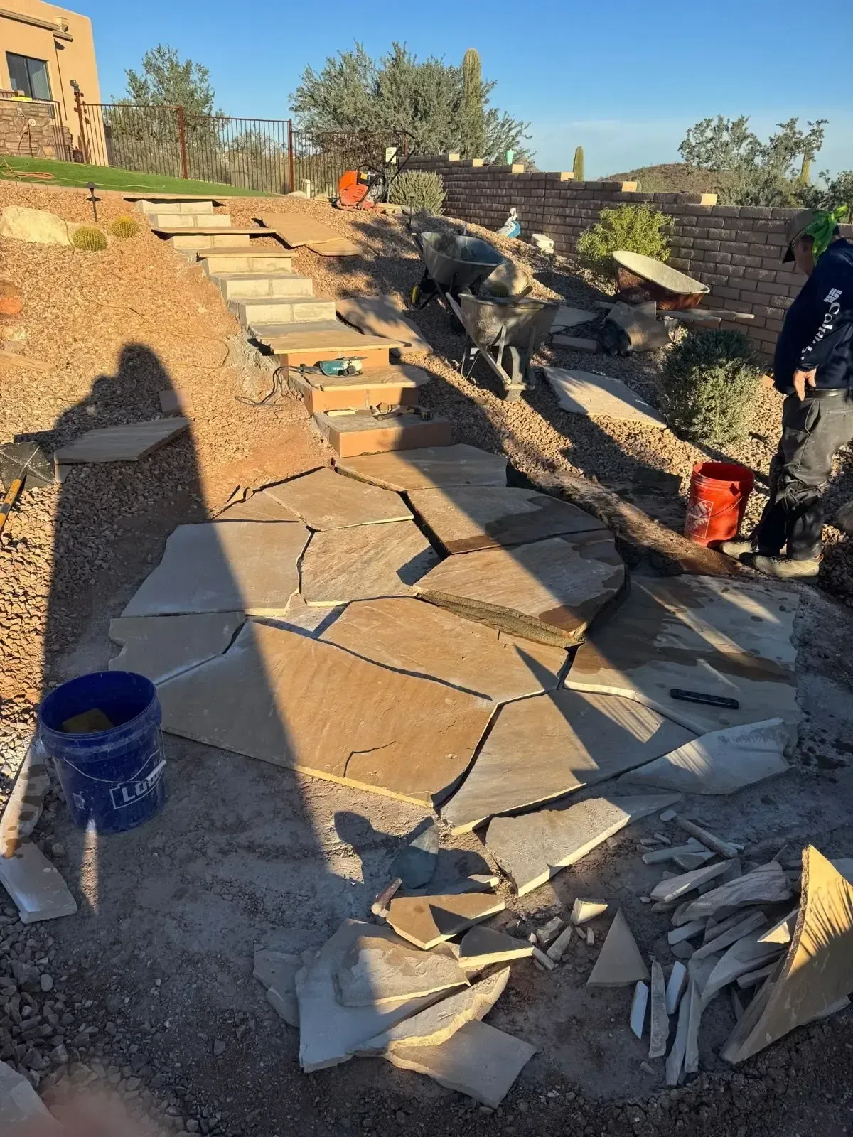 Stone walkway construction in progress on a hillside; steps and path laid with flagstone.