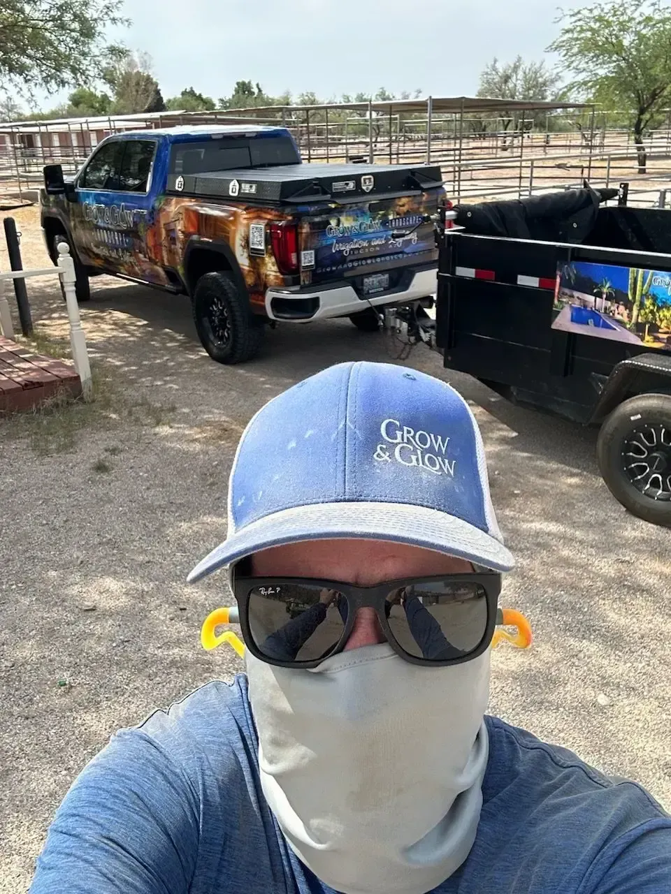 Man in cap and sunglasses in front of a truck towing a trailer.