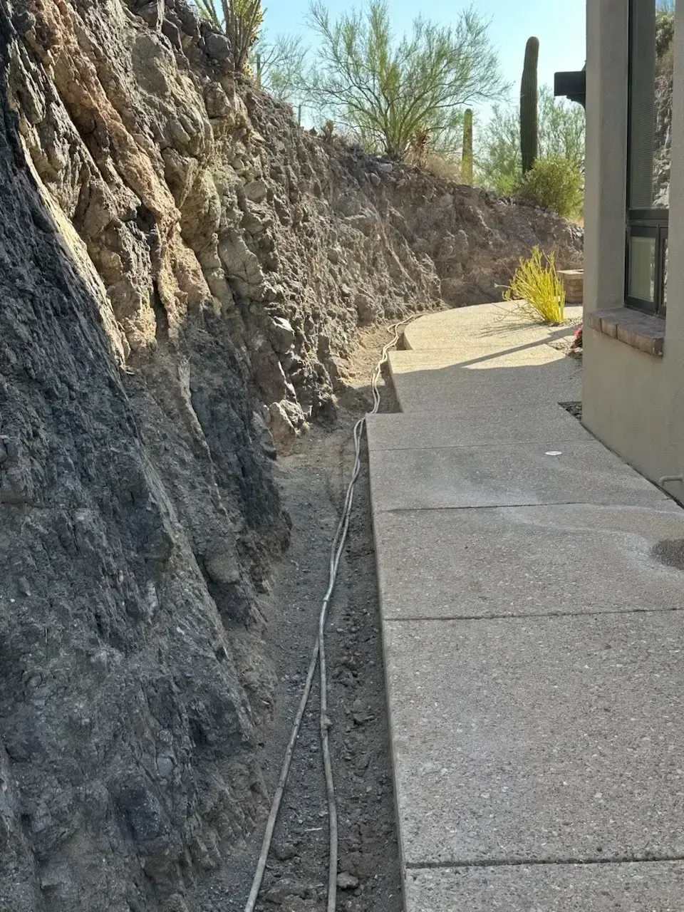 Narrow concrete walkway next to a rocky hillside.