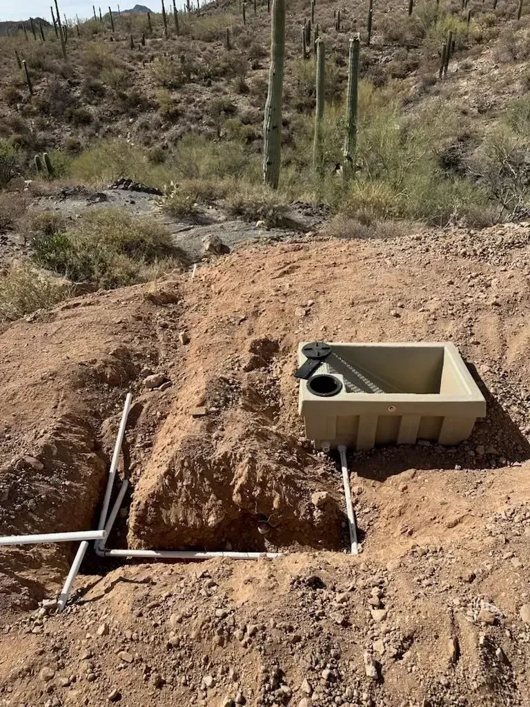 A water trough and PVC piping installed in a desert environment.