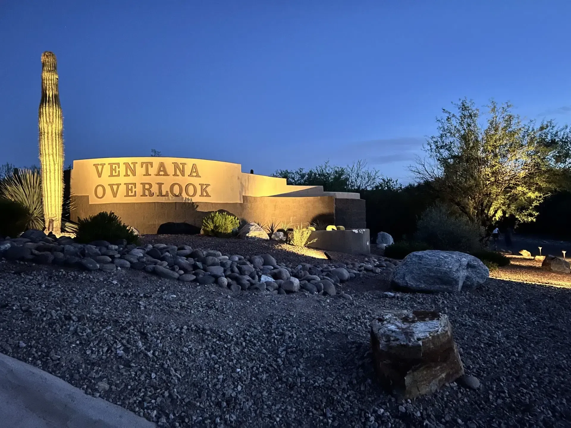 Ventana Overlook sign illuminated at dusk, featuring a saguaro cactus and desert landscape.