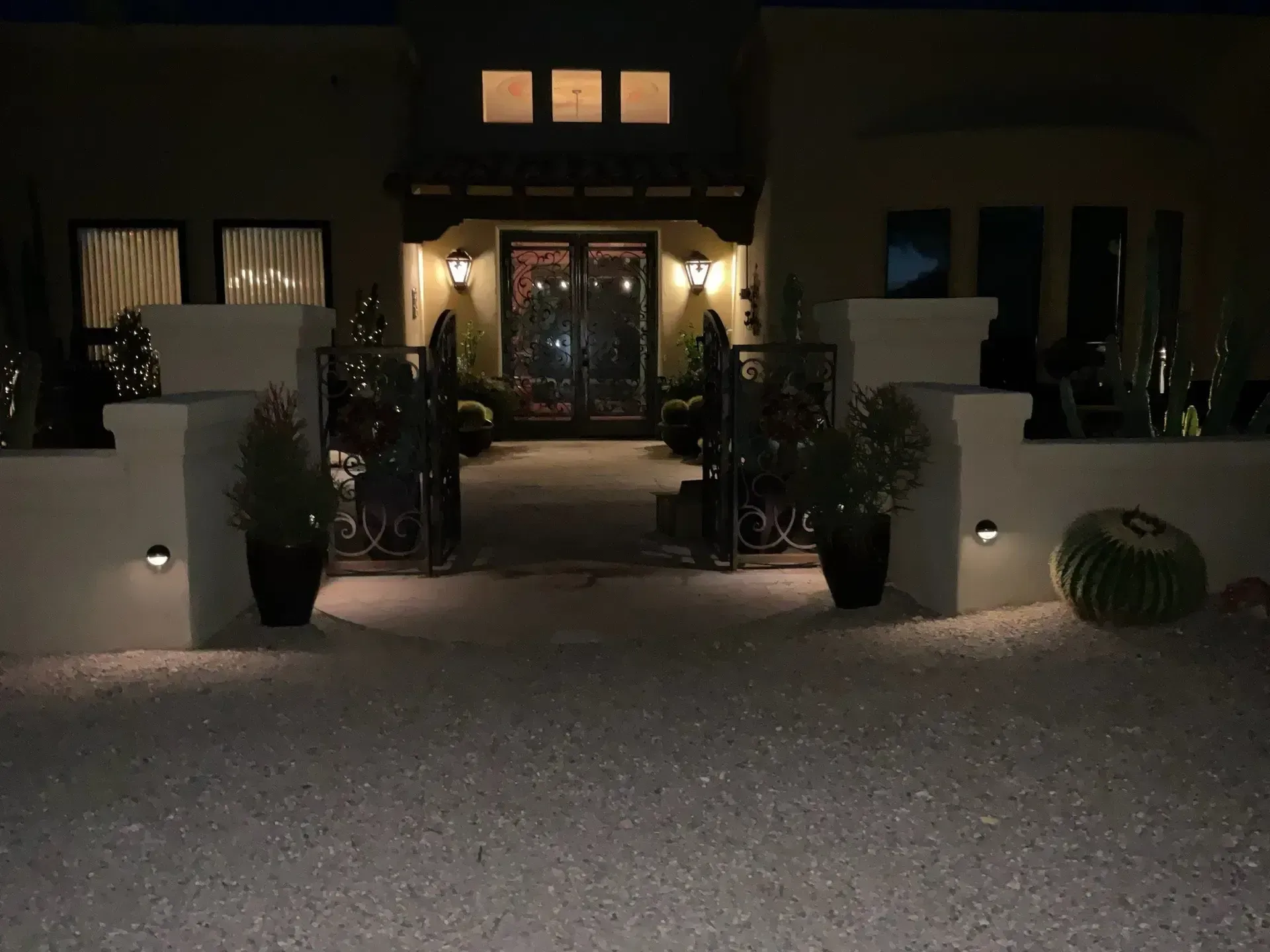 Exterior night view of a house with entryway lights and white gravel driveway.