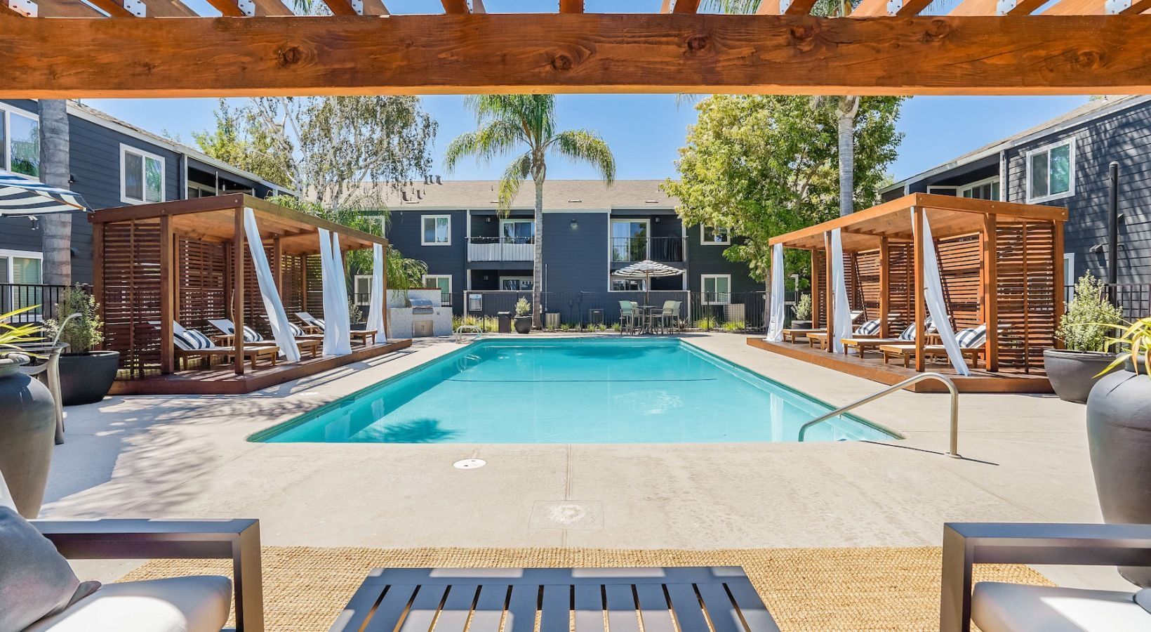 Pool with cabanas and lounge chairs; apartment complex exterior.