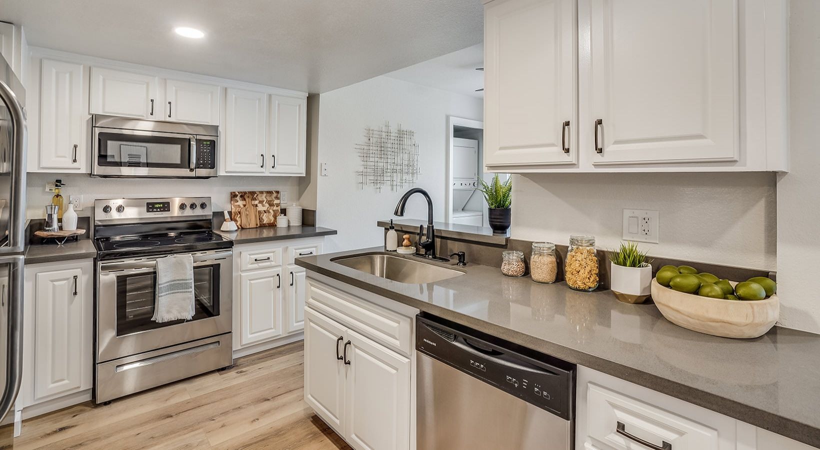 White kitchen with stainless steel appliances and gray countertops.