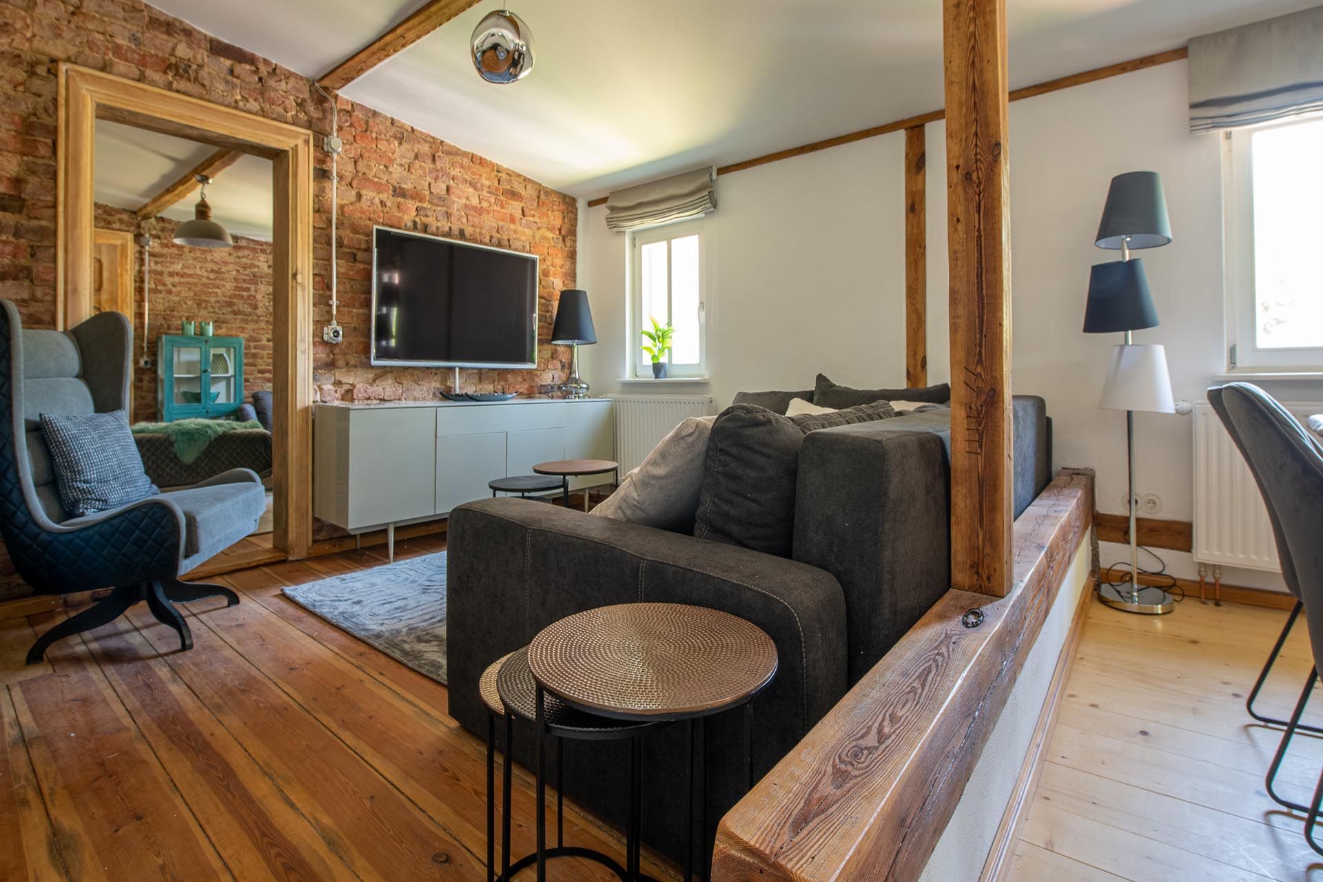 Ein Wohnzimmer mit Couch, Sessel, Tisch und Fernseher.