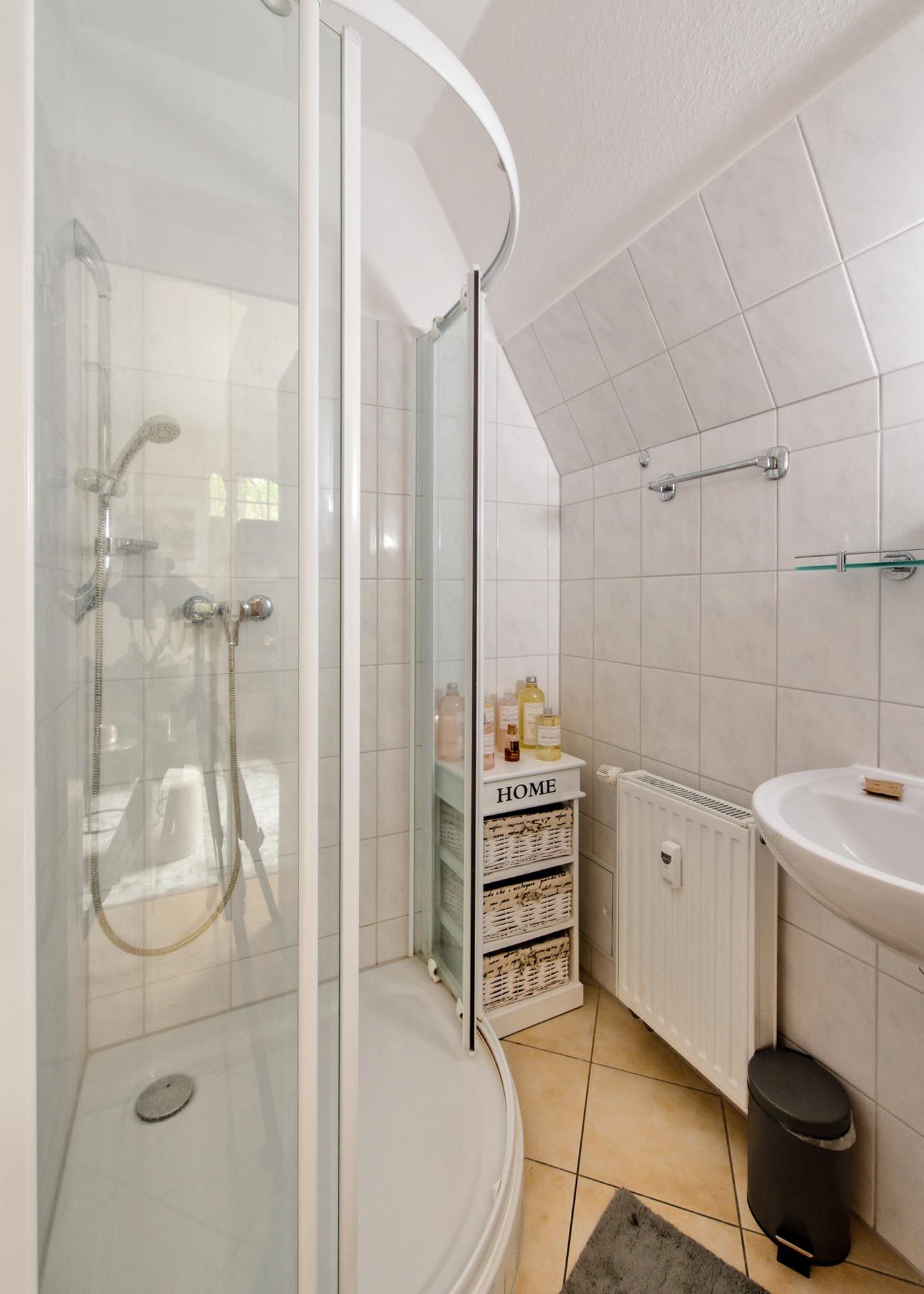 Ein Badezimmer mit Dusche, Waschbecken und Heizkörper.