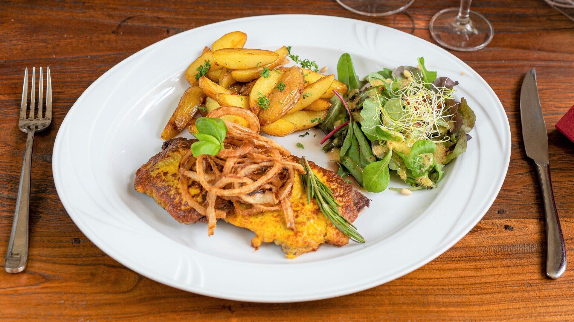 Ein Teller mit Pommes Frites und Salat auf einem Holztisch.