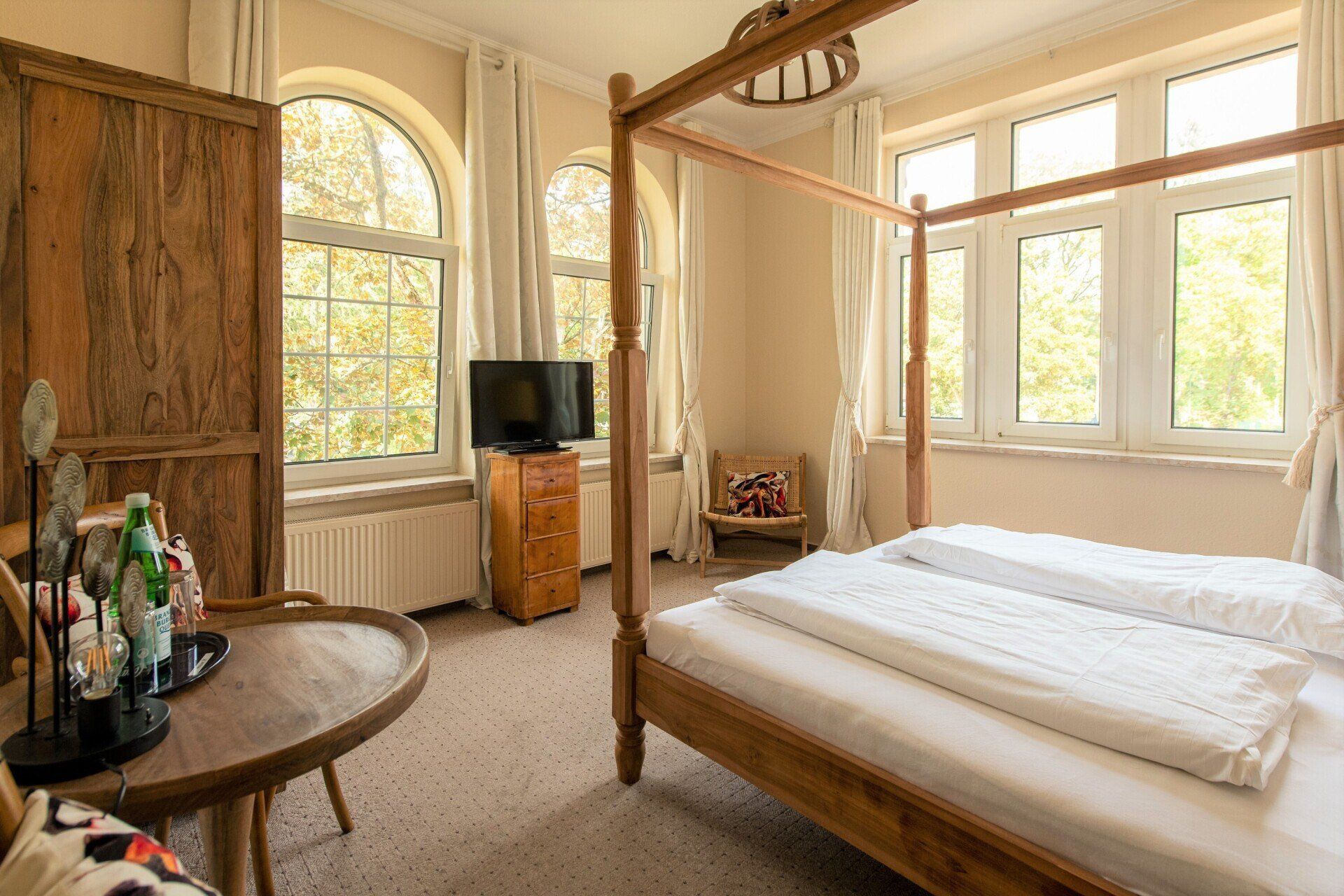 Ein Schlafzimmer mit Himmelbett, Tisch und Fernseher.