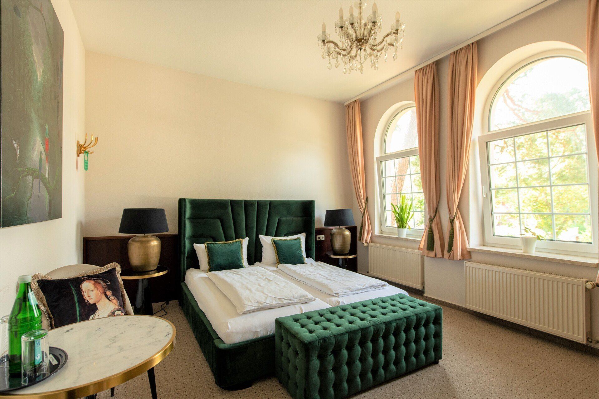Ein Hotelzimmer mit Bett, Ottomane, Tisch und Fenstern.