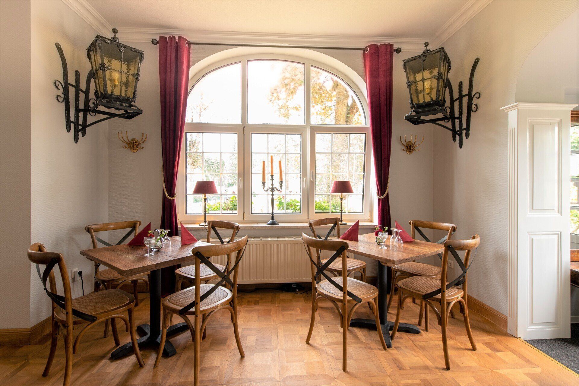 Ein Esszimmer mit Tischen und Stühlen vor einem großen Fenster.