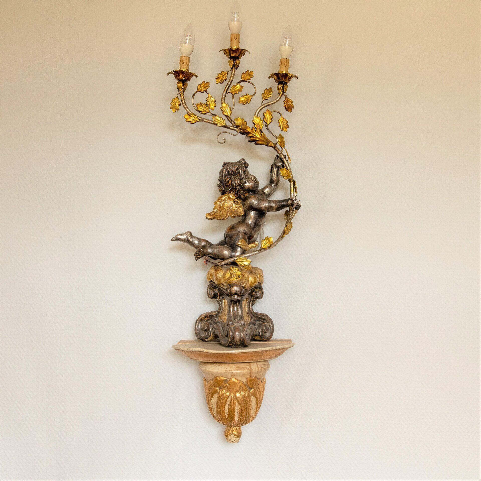 Eine Statue eines Cherubs an einer Wand mit drei Kerzen