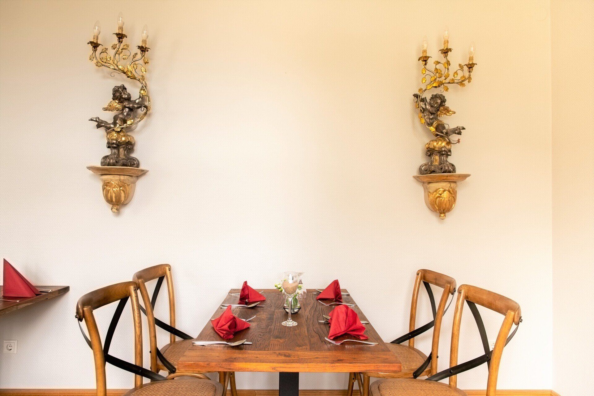 Ein Tisch und Stühle in einem Raum mit Kerzen an der Wand.