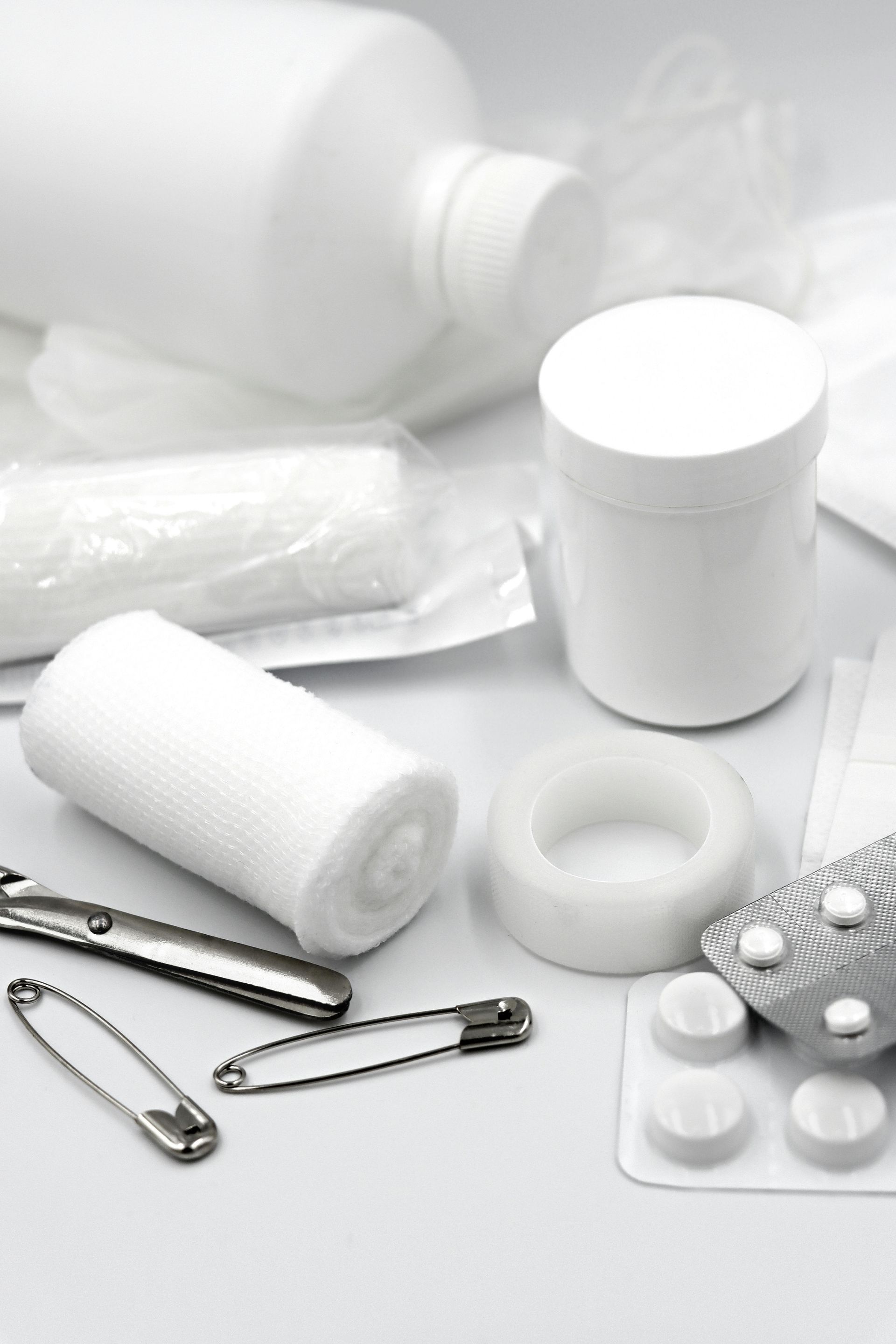 White medical supplies and pills arranged on a light surface, including bandages, tablets, and pill bottles