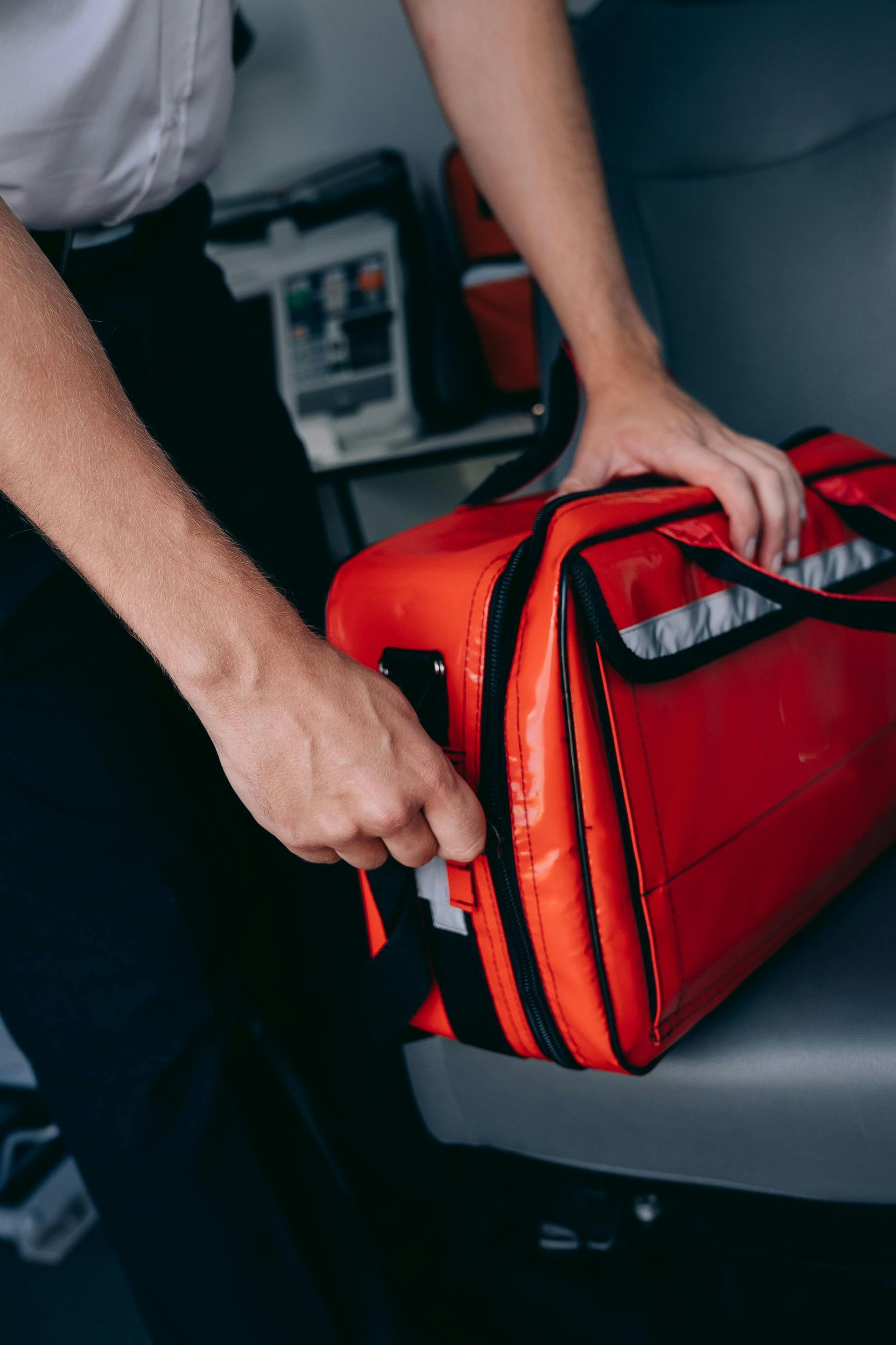Person placing a red emergency bag into a car trunk