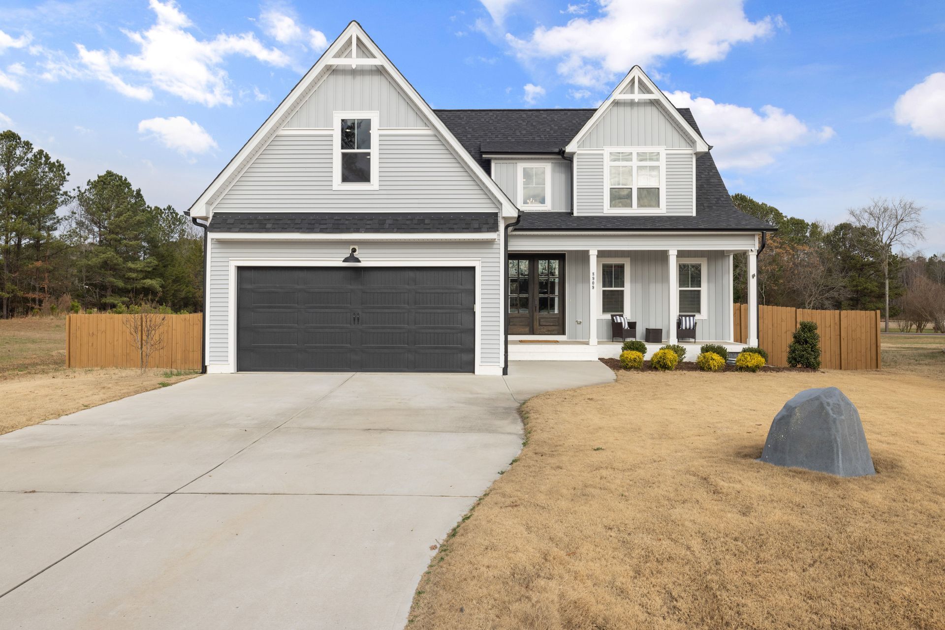 Gray suburban house with a two-car garage, front porch, and concrete driveway