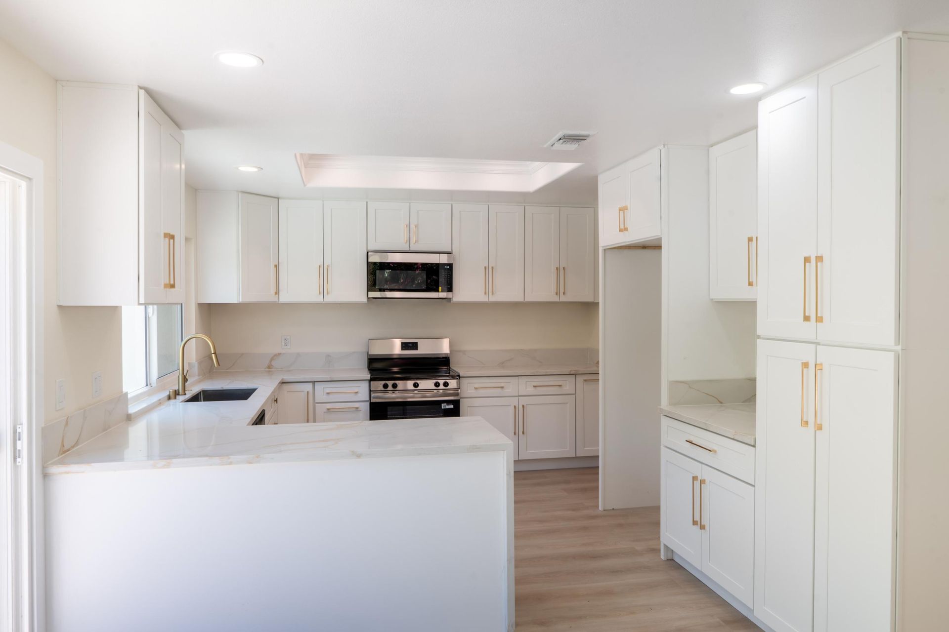 Bright white modern kitchen with an island, built-in oven, and tall cabinets