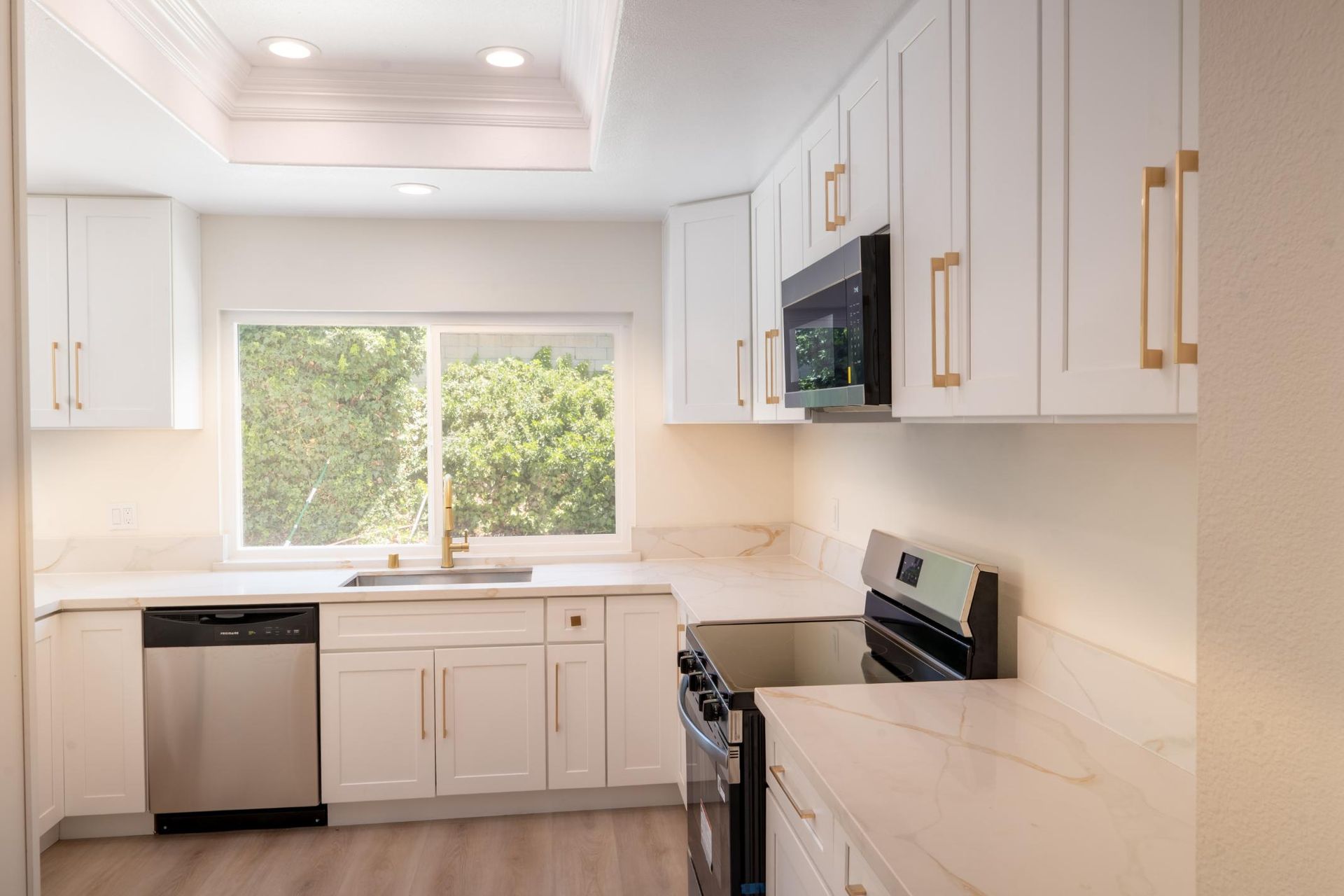 Bright modern kitchen with white cabinets, stainless appliances, and a window over the sink