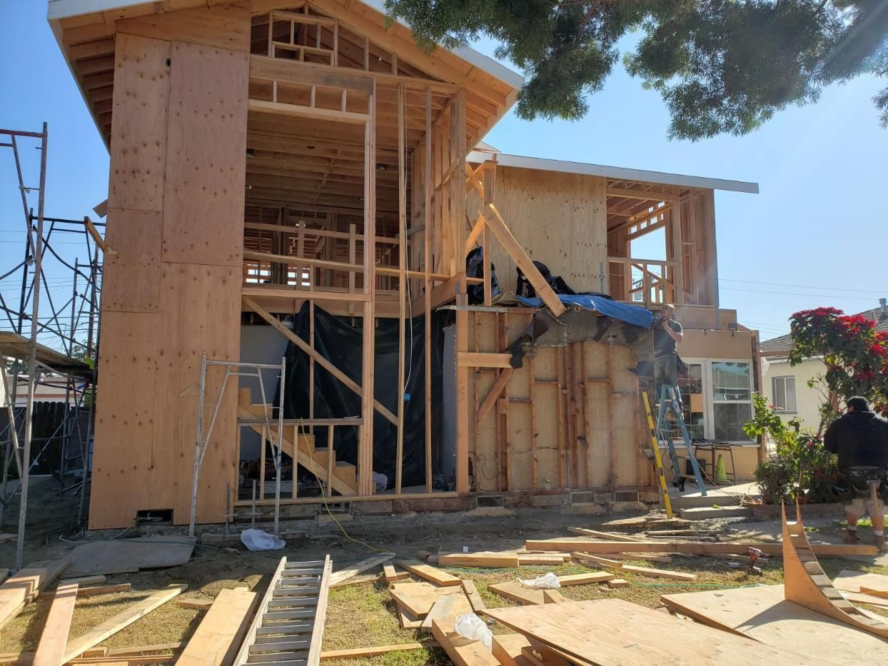 Partially built wooden house with scaffolding and construction debris in front