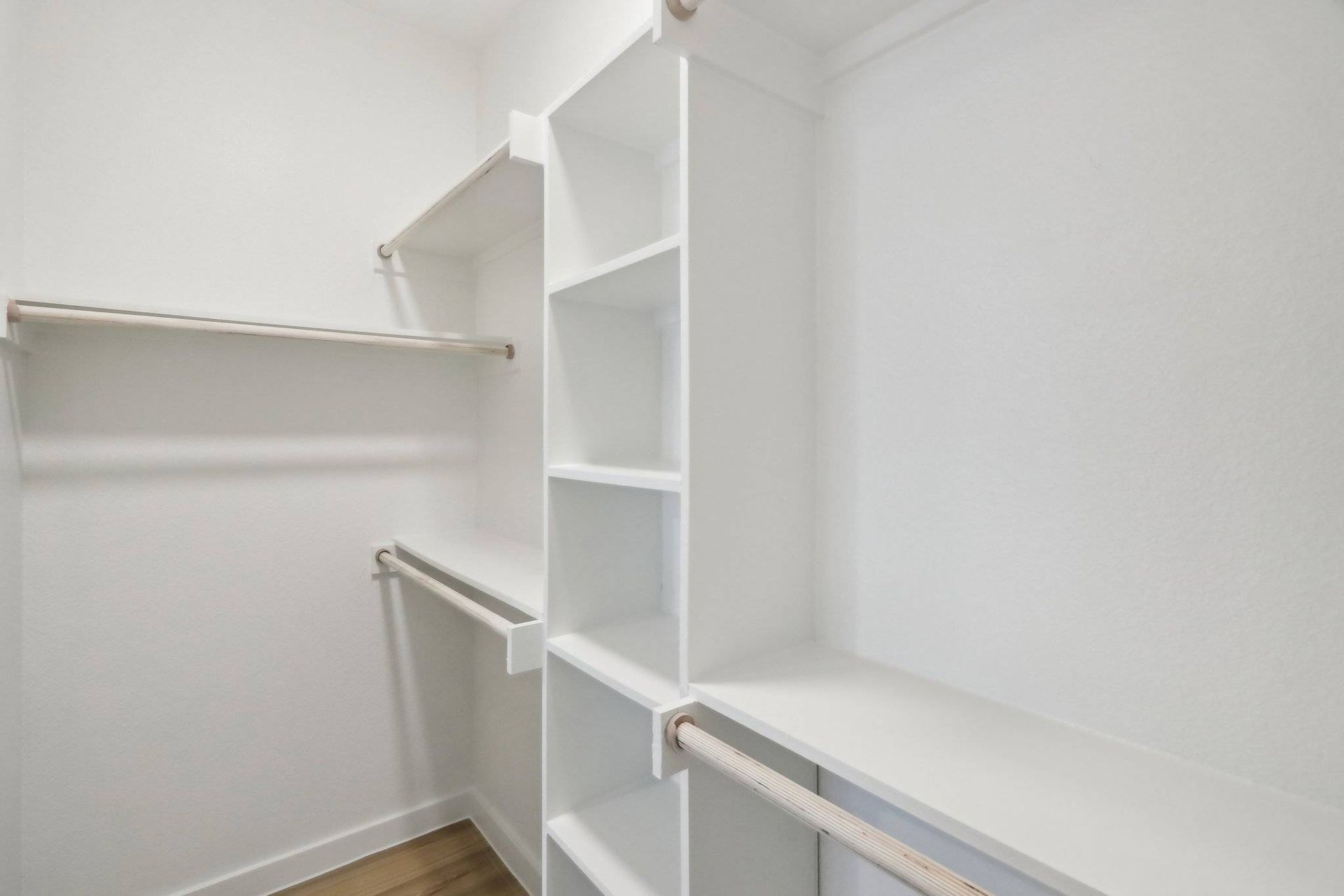 White walk-in closet with built-in shelving and two clothing rods.