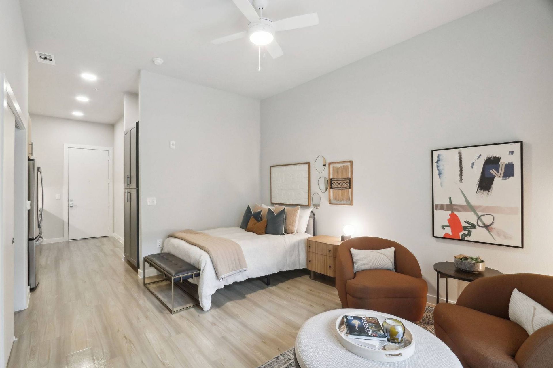 Open-concept apartment interior with a bedroom area, seating, and visible kitchen.