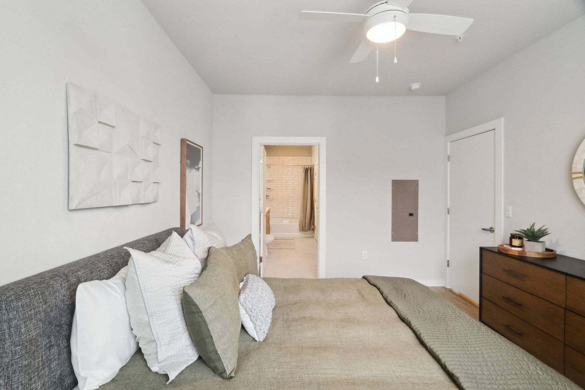 Bedroom in an apartment with a large bed, dresser, and ceiling fan.