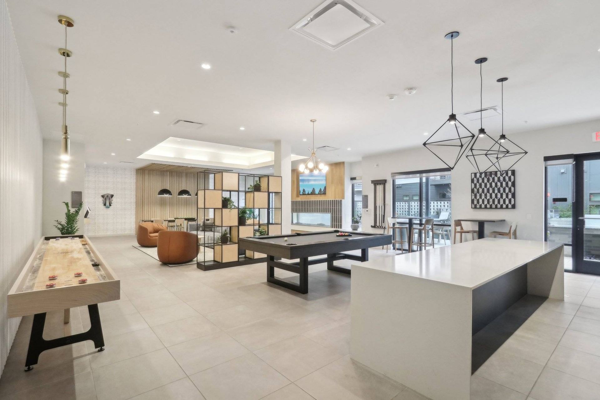 Modern amenity lounge in a multifamily building with a pool table, seating, and a white island counter.