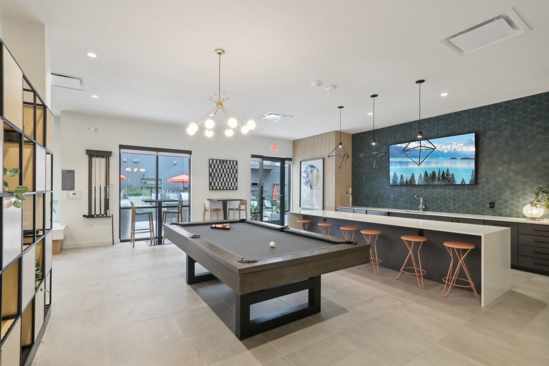 Modern rec room with pool table, bar seating, and large TV.